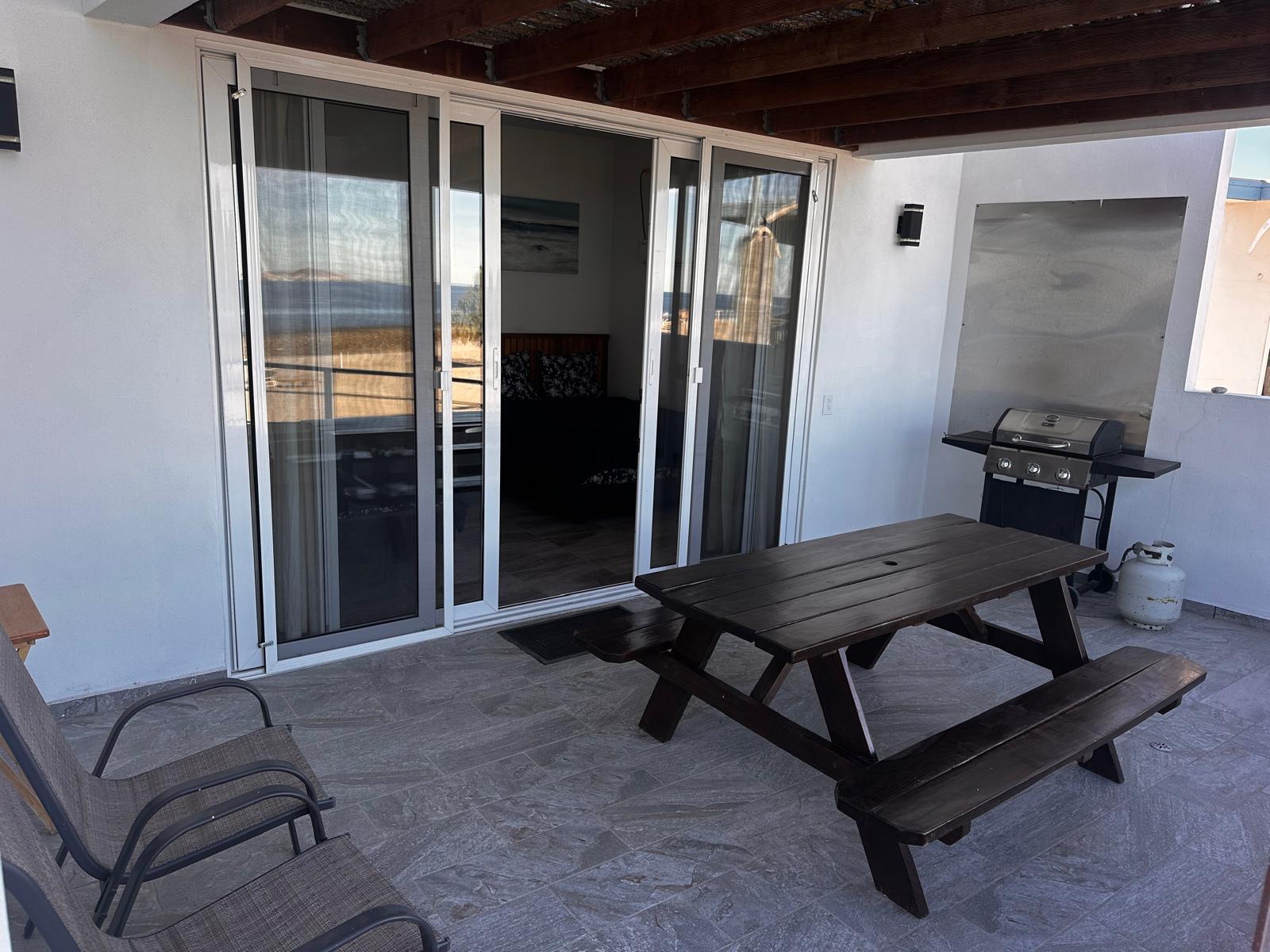 Terraza exterior con mesa de picnic de madera y asador de gas